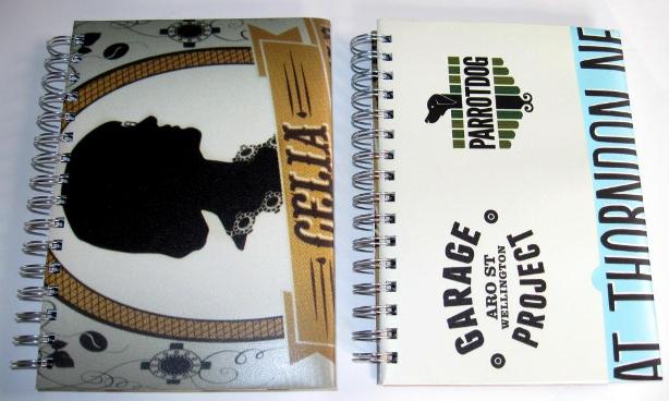 Front view of the recycled poster notebooks featuring Celia Wade-Brown Ale